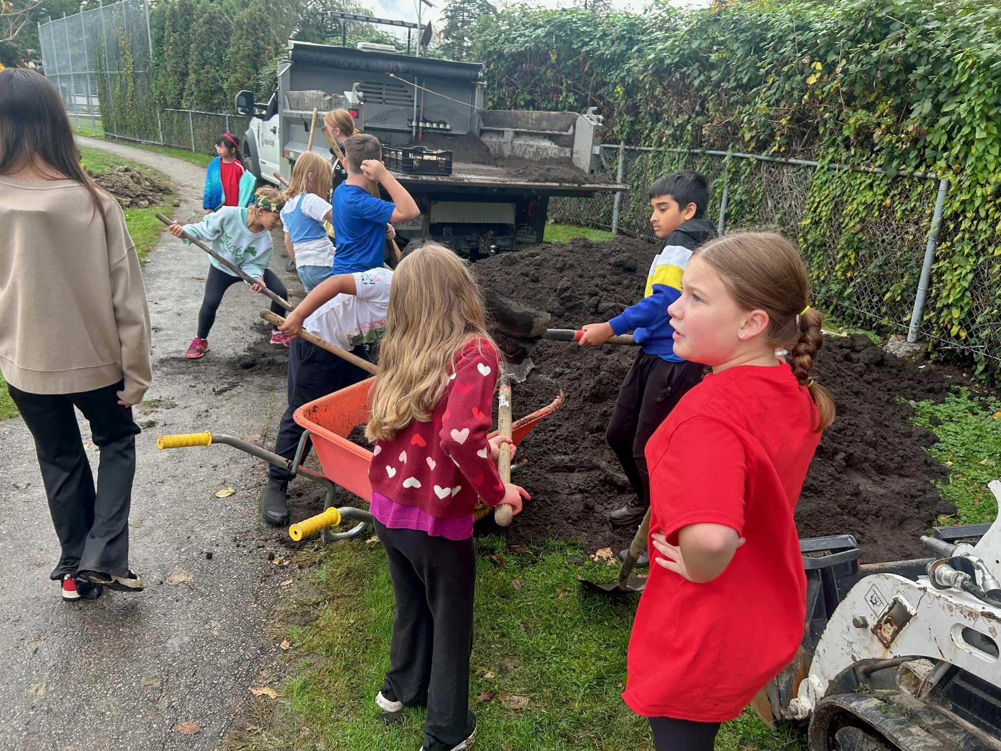 Alexander Robinson Elementary students move soil with shovels as part of a tree planting drive.