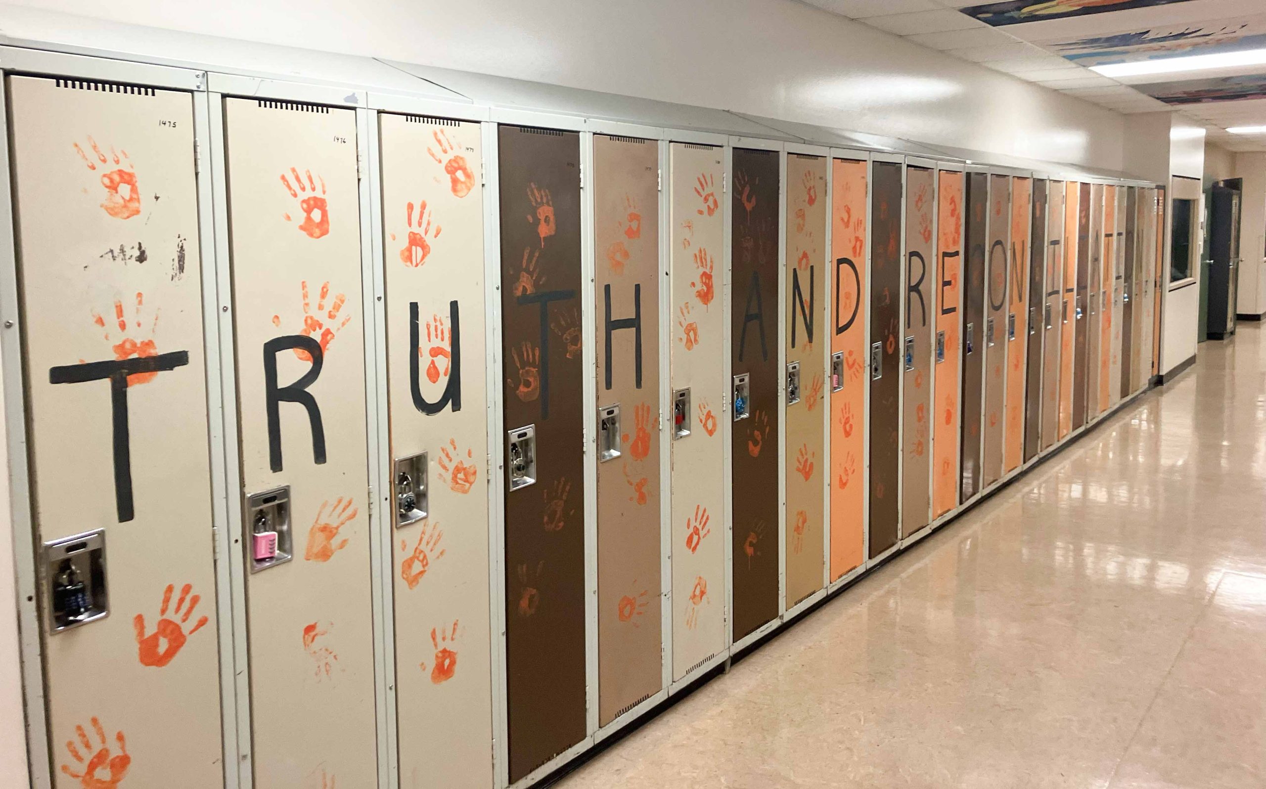 Lockers at Pitt Meadows Secondary decorated with orange handprints and the words "Truth and Reconciliation" written across in black.