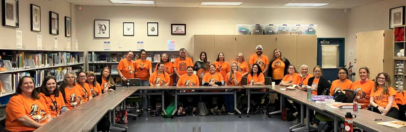 The SD42 Indigenous Education department wears orange shirts and poses for a group photo in the Indigenous Education Resource Library at Westview Secondary.