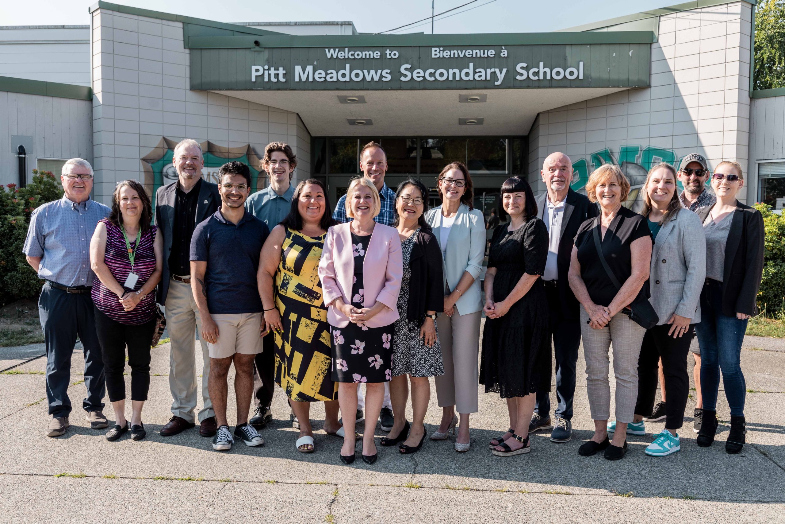 Lisa Beare, MLA for Maple Ridge-Pitt Meadows, stands in front of Pitt Meadows Secondary with city councillors, and SD42 staff and trustees.